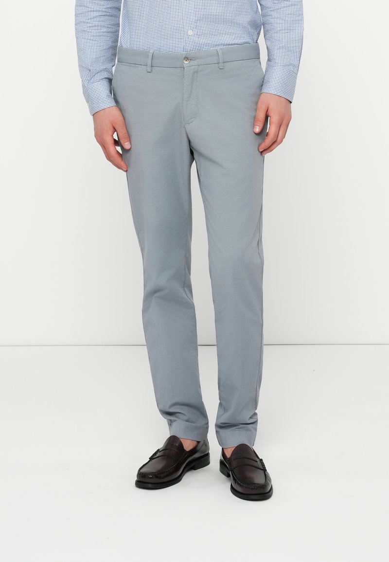 Hellgraue maßgeschneiderte Hosen aus Baumwollmischung mit Knopfverschluss und Seitentaschen, kombiniert mit dunkelbraunen Loafers.