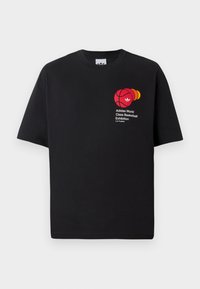 Sort bomulds T-shirt med rund hals, korte ærmer, med et rødt basketball-grafik og tekst, der læser "Adidas World Class Basketball Exhibition."