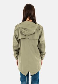 Chaqueta resistente al agua de color verde claro, con capucha, puños elásticos y un respaldo más largo. Presenta un diseño simple y aerodinámico sin acentos adicionales.