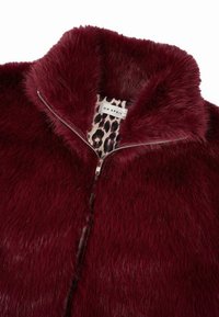 Bordo dirbtinio kailio striukė su užtrauktuku ir plačiu apykakle. Vidaus pamušalas turi leopardų raštą. Minkšta tekstūra ir storas kailis.