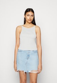 Camisola cinza canelada com um decote largo, combinada com uma saia de denim azul-claro com bordas desgastadas e uma silhueta justa.