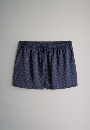 Pantaloncini blu navy con motivo a pois bianchi, vita elasticizzata e vestibilità ampia. Realizzati in tessuto leggero per garantire comfort.