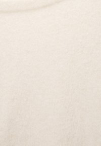 Tissu tricoté de couleur crème avec une texture douce, présentant un motif chiné subtil et un tissage lisse et uniforme sur toute la surface.