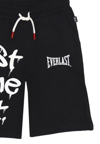 Pantaloni corti neri realizzati in un mix di cotone e poliestere, con testo grafico bianco e logo Everlast. Il cordoncino ha punte rosse.