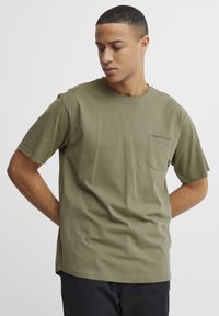 Olive green, short-sleeve t-shirt made of cotton, featuring a crew neck and a chest pocket. Simple design with a relaxed fit.