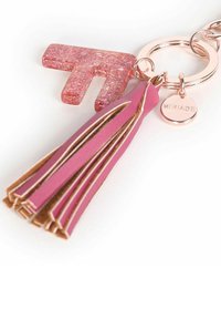 Portachiavi con un charm in acrilico glitterato rosa a forma di "T", abbinato a una frangia in pelle rosa. L'anello metallico attaccato è in oro rosa.