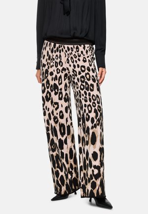Leoprind-Hosen mit weitem Bein aus einem weichen Stoff, auffälligem schwarz-beigem Muster und einem elastischen Bund, kombiniert mit einem schwarzen Oberteil.