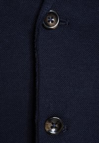 Cardigan lavorato a maglia blu navy con collo tondo, chiusura con bottoni in metallo lucido e tessuto testurizzato.