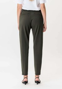 Olive green długie spodnie o dopasowanym kroju, charakteryzujące się gładką fakturą, dwiema tylnymi kieszeniami i nogawką sięgającą nad kostkę.