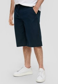 Shorts bleu marine en tissu léger, offrant une coupe d�écontractée, des poches latérales et un ourlet droit ; associés à des baskets blanches.