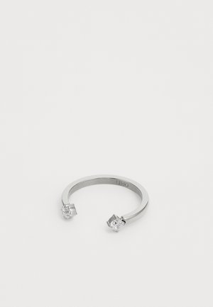 Srebrny pierścień otwarty z dwoma przezroczystymi, okrągłymi kamieniami szlachetnymi osadzonymi na każdym końcu, prezentowany na białym tle.