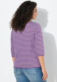 Lila-weiß gestreifter Dreiviertelarm-Top mit Rundhalsausschnitt, bietet eine lockere Passform und besteht aus weichem, strukturiertem Baumwollmaterial.