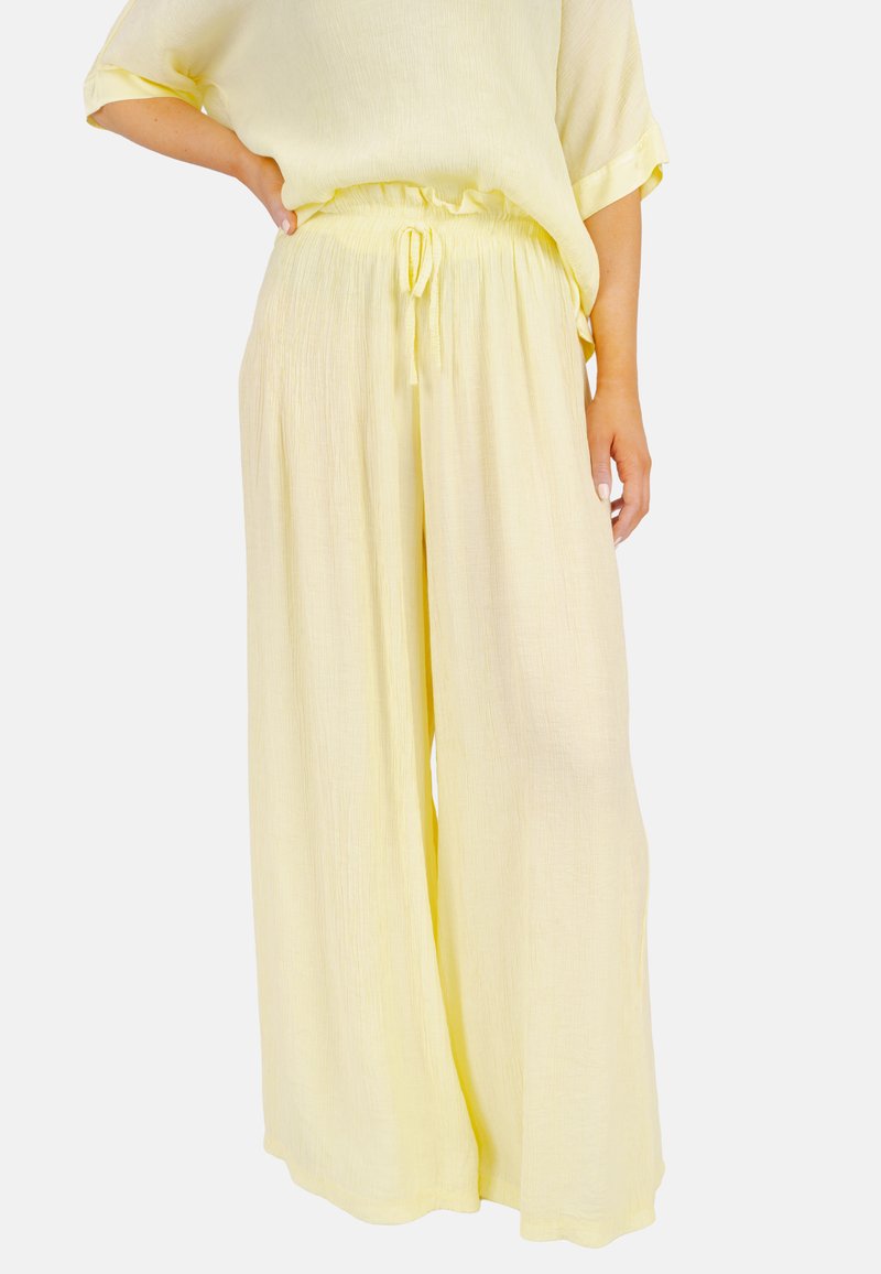 Helle gelbe, weit geschnittene Hosen aus einem strukturierten Stoff, mit einem Kordelzugbund und fließender Silhouette.