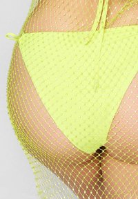 Neon żółte bikini dolne z siateczkowym wykończeniem, zdobione małymi kryształkami i zawiązywane po bokach, podkreślające strukturalny design.
