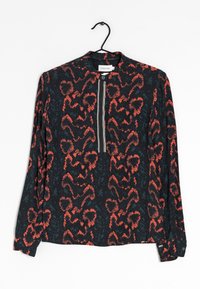 Chemise noire à manches longues avec un imprimé abstrait de serpent rouge et bleu, une fermeture éclair à l'avant et des poignets boutonnés. Suspendue à un crochet.