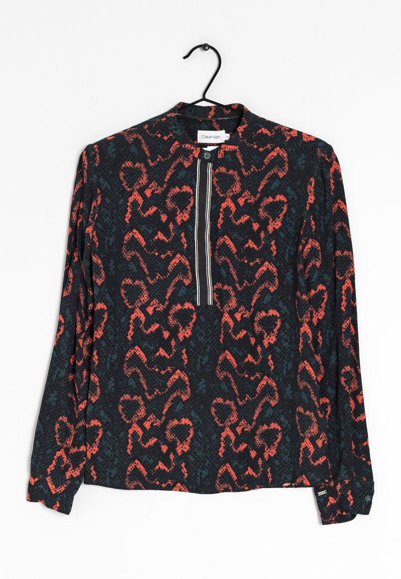 Chemise noire à manches longues avec un imprimé abstrait de serpent rouge et bleu, une fermeture éclair à l'avant et des poignets boutonnés. Suspendue à un crochet.