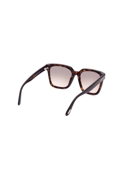 Lunettes de soleil à monture carrée avec un motif écaille tortue, des verres dégradés et des branches noires élégantes. Présente des accents métalliques sur les branches.