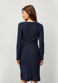 Marineblaues Langarmkleid mit taillierter Passform und knielangem Saum. Glatte Textur mit einem schlichten, klassischen Design und ohne Verzierungen.