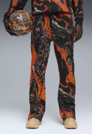Pantalon de basketball dans un motif abstrait noir, orange et violet. Fabriqué en tissu lisse, il présente une coupe décontractée et une taille élastique.