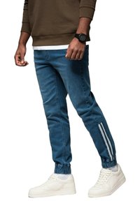 Joggery dżinsowe w jasnoniebieskim kolorze z elastycznymi mankietami, z białymi paskami po bokach i dopasowanym krojem. W połączeniu z białymi sneakersami.