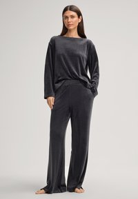 Fluwelen loungewear-set in donkergrijs, met een loszittend T-shirt met lange mouwen en een wijde broek, allemaal met een zachte textuur en eenvoudig ontwerp.