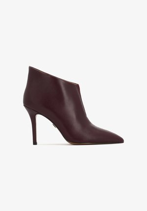 Bottines en cuir bordeaux avec un bout pointu, un talon aiguille et une texture lisse. Présente un design avec une découpe sur le côté pour un détail supplémentaire.