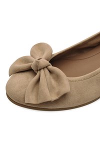 Bailarina de ante beige con un gran lazo en la puntera, forma redondeada y parte superior de textura suave y lisa.