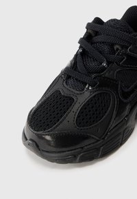 Sapatilha desportiva preta com parte superior em malha texturizada e detalhes em pele sintética, design com atacadores e colarinho acolchoado.