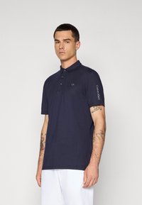 Námornícky polo tričko vyrobené z m�äkkej látky s trojkontaktným zapínaním. Obsahuje logo 'CK' na hrudi a text 'Calvin Klein' na rukáve.
