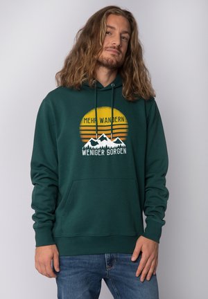 Hoodie vert foncé avec une poche avant, présentant une illustration graphique de montagnes et d'un coucher de soleil, avec du texte en blanc et jaune.