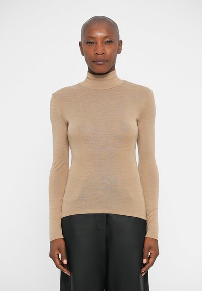Haut à col roulé beige à manches longues, fabriqué dans un tissu léger et lisse avec un design ajusté. Texture douce, construction sans coutures.
