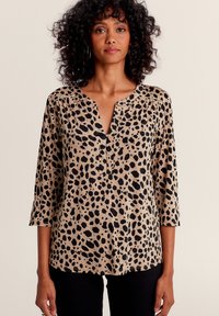 Beige Bluse mit schwarzem Leopardenmuster, V-Ausschnitt und dreiviertel Ärmeln, aus glattem Stoff mit lässiger Passform.