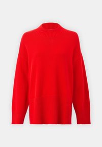 Pull rouge en tricot avec un col montant côtelé, des épaules tombantes et des manches larges. La texture est lisse, avec un motif côtelé à l'ourlet.