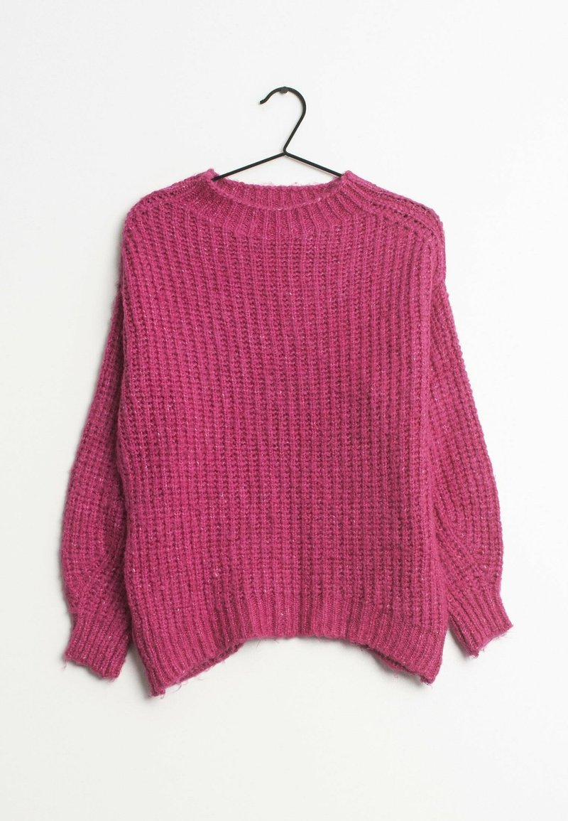 Pull en grosse maille rose avec poignets et ourlet côtelés suspendu à un cintre noir sur fond blanc.