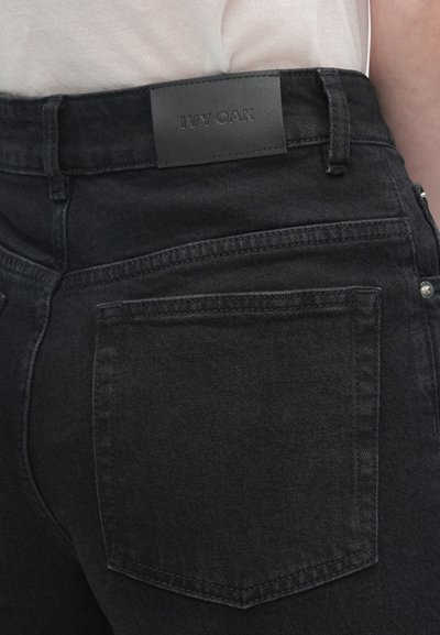 Czarne dżinsy z denimu o matowym wykończeniu, z naszywką ze skóry oznaczoną "IVY OAK" oraz kontrastującym przeszyciem wzdłuż kieszeni.