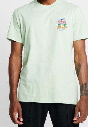 Mintgrøn kortærmet t-shirt af bomuld med rund hals. Har en farverig logo på venstre bryst med tekst og grafiske detaljer.