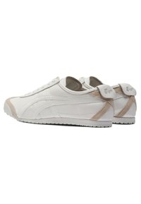 Hvide lædersneakers med beige accenter, rund tå og flad gummisål. Har en quiltet design og logo på hælen.