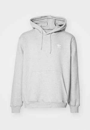 Szürke kapucnis pulóver kenguruzsebből, állítható húzózsinórral ellátott kapucnival és kis fehér logóval a mellkason. Puha, textúrált anyagból készült.