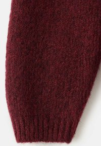 Mâneca puloverului tricotat în nuanță burgundă cu un material texturat, pufos. Prezintă detalii cu mansetă ondulată pentru o potrivire strânsă.