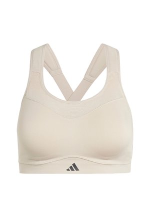 Bra sportivo beige con design senza cuciture, spalline incrociate e un piccolo logo nero in basso. Realizzato in tessuto morbido e elasticizzato.