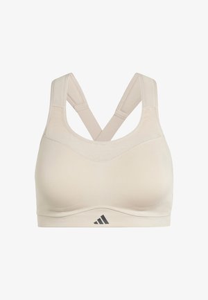 Bra sportivo beige con design senza cuciture, spalline incrociate e un piccolo logo nero in basso. Realizzato in tessuto morbido e elasticizzato.