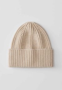 Berretto a maglia beige con texture a coste, caratterizzato da un risvolto e un motivo a cuciture verticali. Realizzato in un materiale morbido e elasticizzato.