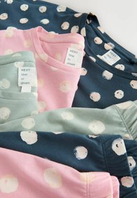 Vier kurzärmlige Hemden: pink, grün und navy, jeweils mit weißen, runden Mustern. Die Etiketten tragen die Aufschriften "NEXT" und "Zeit zu träumen." Aus weichem Baumwollmaterial.