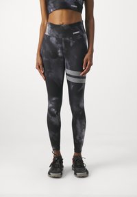 Svart och grå batikmönstrade leggings med hög midja och reflektionsstrimmor, i kombination med svarta träningsskor.