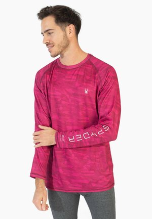 Langærmet skjorte i klar rosa med et tekstureret mønster og kontrastfarvet syning. Har branding trykt på ærmet.