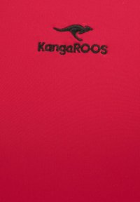 Roter Stoff mit einer glatten Textur, der ein schwarzes gesticktes Känguru-Logo und das Wort "KangaROOS" darunter zeigt.