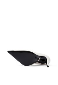 Scarpa con tacco alto bianca e nera con punta affusolata, caratterizzata da una finitura lucida, una silhouette elegante e un sottile accento metallico vicino al tacco.