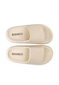 Beige slaidu sandales ar teksturētu augšu, kurām ir atvērta pirksta daļa un divu siksnu dizains. "BIANCO" drukāts uz zolītes.