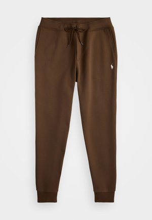 Brown sweatpants with an elastic waistband, adjustable drawstring, two side pockets, and a small white logo on the thigh. Cotton blend fabric.
