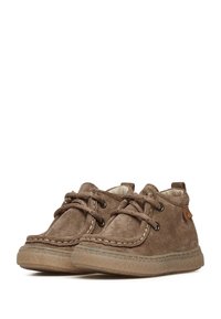 Scarpe in suede marrone con punta rotonda, lacci in cotone e dettagli di cucitura. Suola in gomma con finitura testurizzata e piccolo logo laterale.